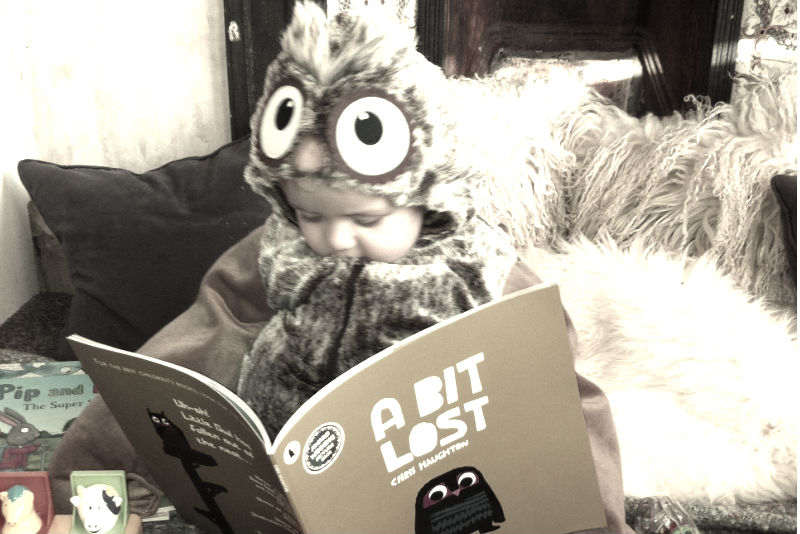 toddler dressed as an owl reading A Bit Lost