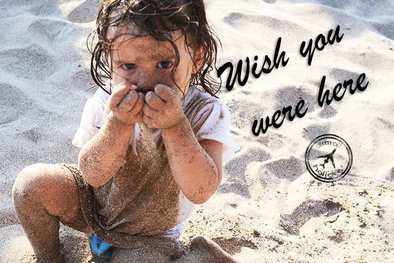 Wish you were here! Postcard with a toddler covered in sand.